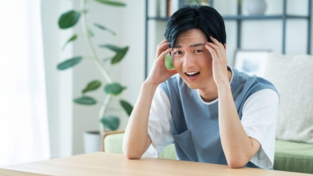 両手を頭に当て後悔する男性