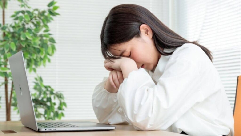 机に肘をつき悩む若い女性