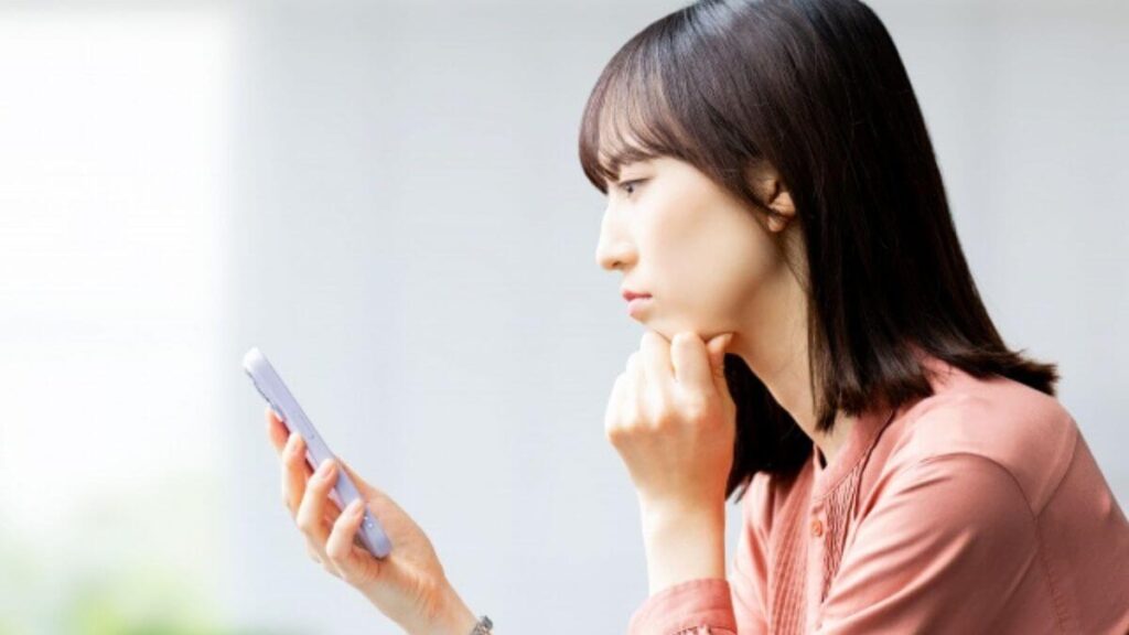 スマホを持ちながら考え事をする若い女性
