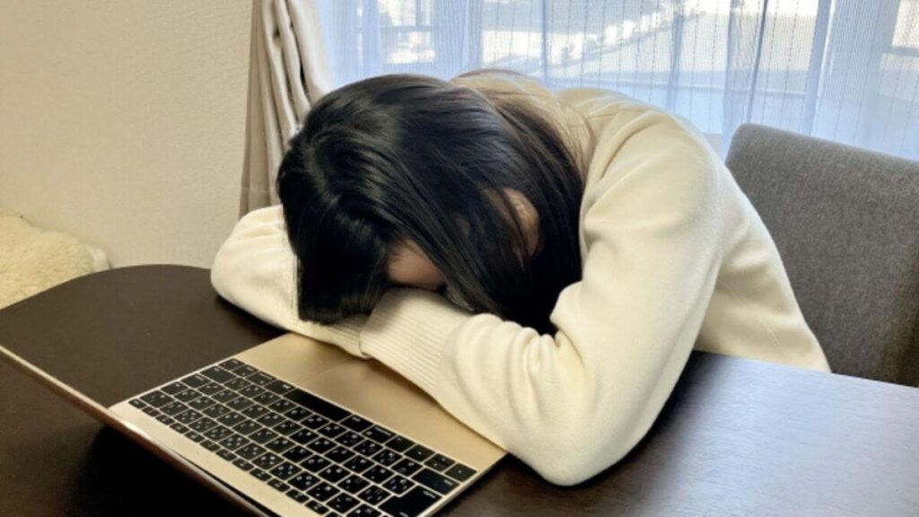 机に伏せて体調が悪そうな女性