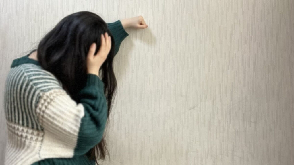 落ち込み壁に手をつく女性