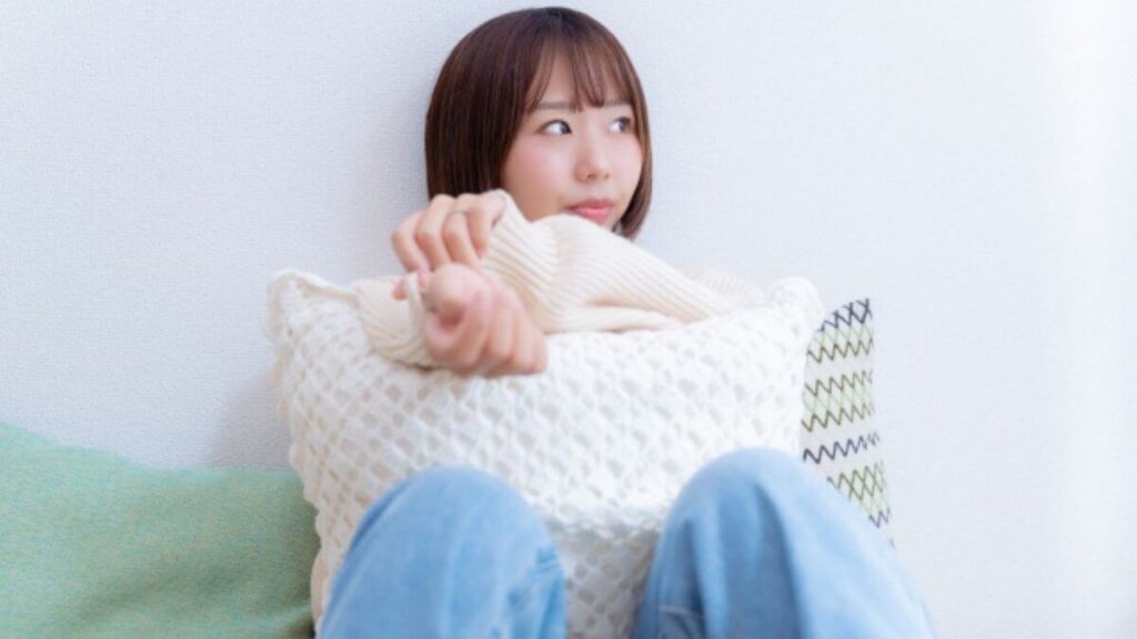 クッションを抱え不満顔をする若い女性