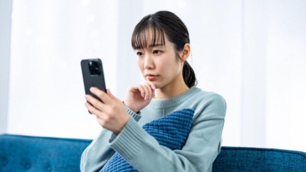 考えながらスマホを持つ女性