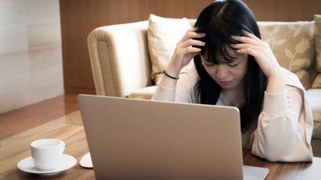 室内で落ち込んだ表情をする若い女性